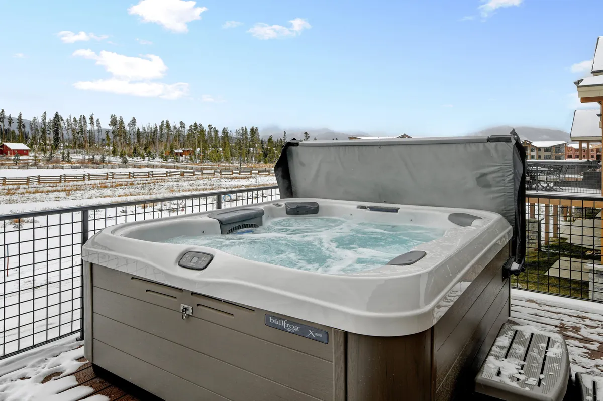 This exterior shot captures the private hot tub surrounded by a wooden fence and scenic landscape. The image evokes moments of relaxation after a day of adventure, aligning with the section's mention of unwinding in the hot tub and making family memories.