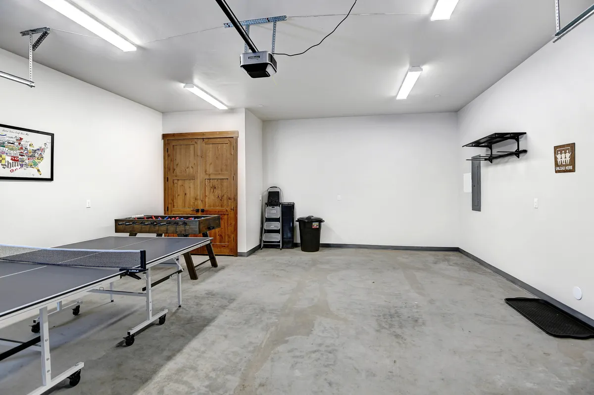 A playful interior scene showing a ping pong table and foosball table with wooden cabinets and shelves that could house board games or books, inviting friendly competitions and easy access to classic games.
