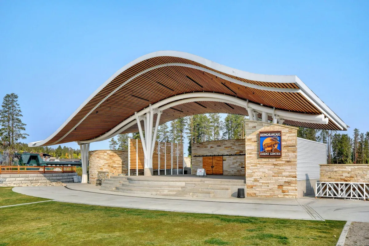 This image shows the exterior of an event center with a distinctive curved roof structure and stone façade. The prominent event center signage sets the scene for community gatherings and live entertainment events, emphasizing the local concert and festival atmosphere alluded to in the section content.